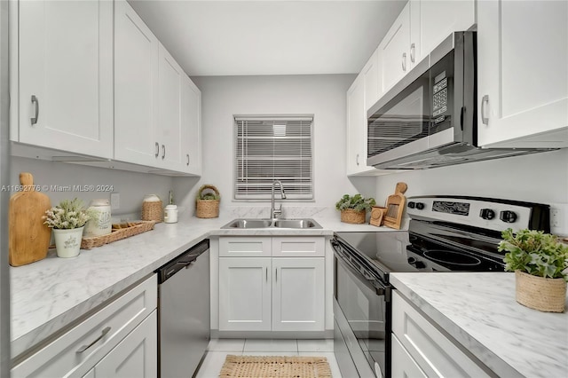 kitchen featuring white cabinets, sink, light tile patterned floors, light stone counters, and stainless steel appliances