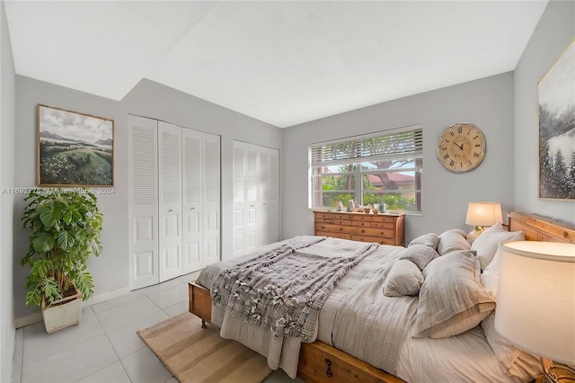 bedroom with light tile patterned floors and multiple closets