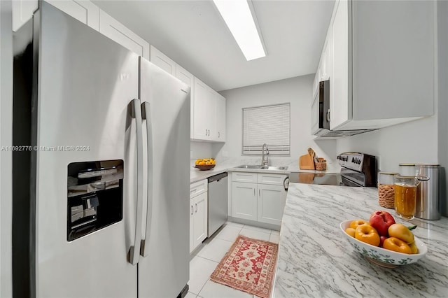 kitchen featuring white cabinetry, sink, light tile patterned floors, and stainless steel appliances