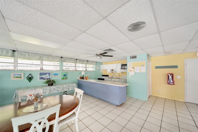 kitchen featuring kitchen peninsula, a drop ceiling, ceiling fan, light tile patterned floors, and white cabinetry