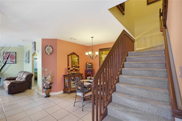 stairs featuring tile patterned flooring and an inviting chandelier