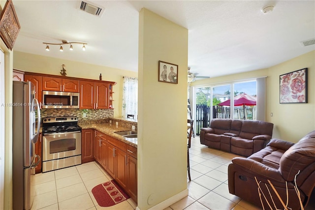 kitchen featuring sink, light tile patterned floors, backsplash, and appliances with stainless steel finishes