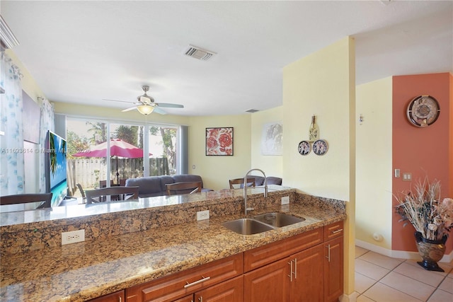 kitchen featuring ceiling fan, sink, light tile patterned floors, and light stone countertops