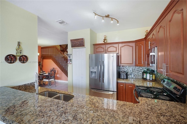 kitchen featuring light stone countertops, appliances with stainless steel finishes, backsplash, kitchen peninsula, and sink