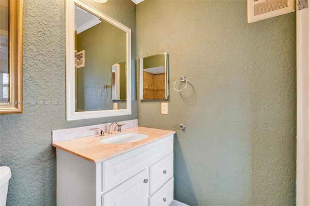 bathroom with vanity, toilet, and crown molding