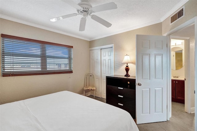 bedroom with ceiling fan, a textured ceiling, a closet, light tile patterned flooring, and ornamental molding