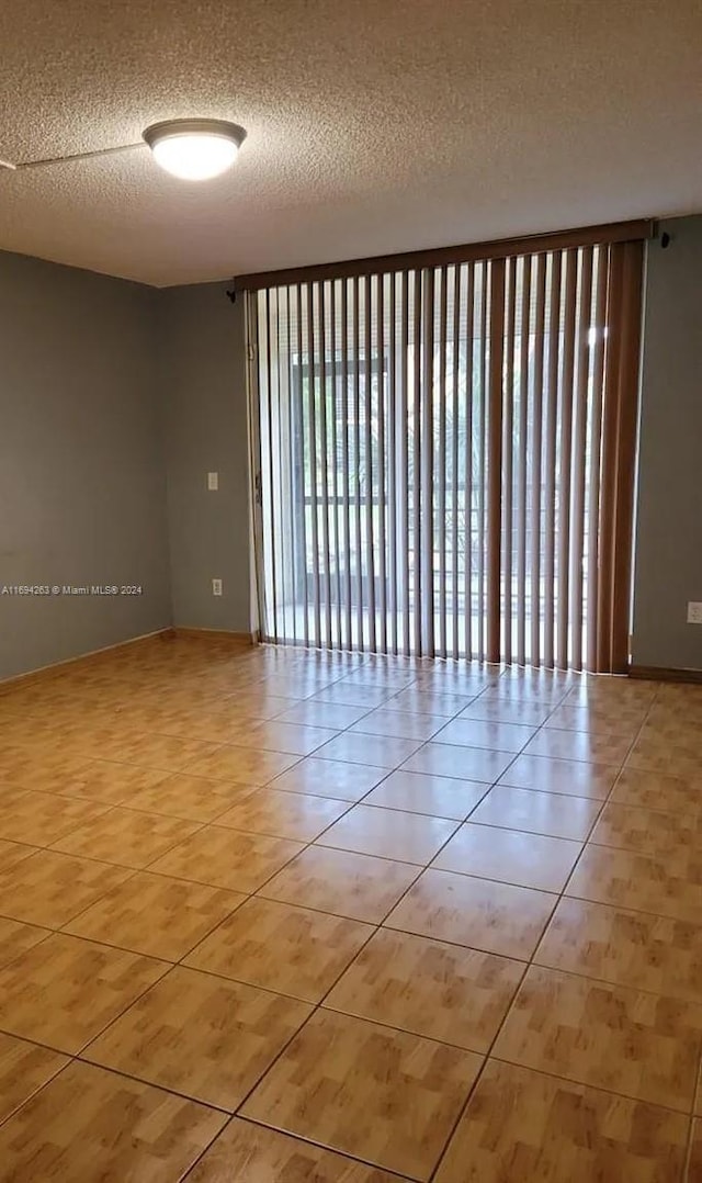 spare room featuring light tile patterned flooring and a textured ceiling