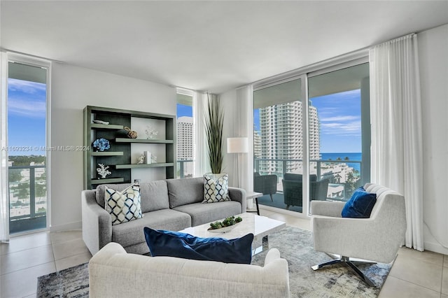 living room with floor to ceiling windows, a water view, and light tile patterned floors