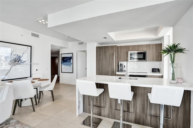 kitchen featuring a kitchen breakfast bar, light tile patterned floors, and kitchen peninsula