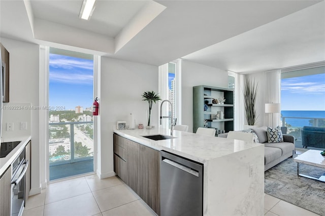 kitchen featuring a water view, sink, light tile patterned flooring, kitchen peninsula, and stainless steel appliances