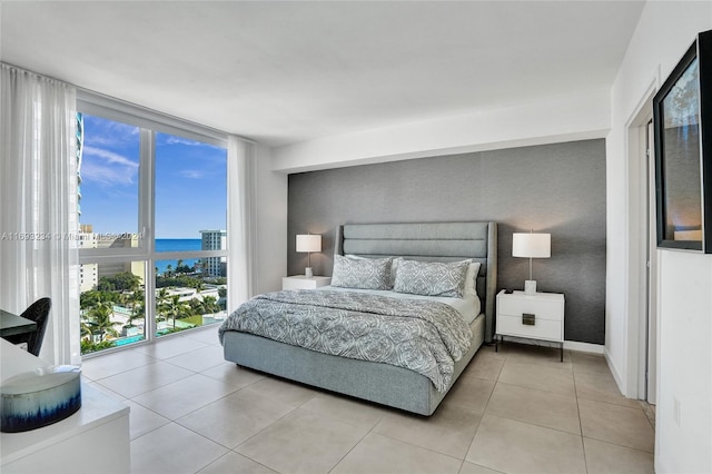 bedroom with a water view, light tile patterned floors, and multiple windows