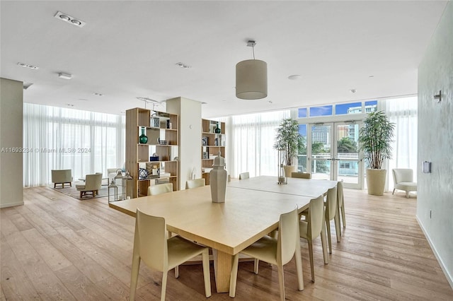 dining room featuring light wood-type flooring, a wall of windows, and french doors