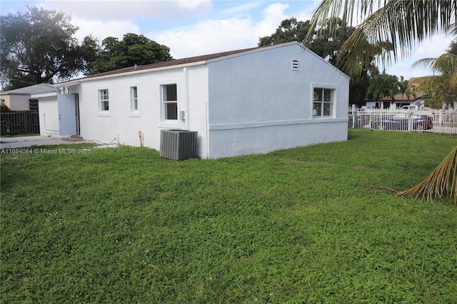 view of side of property featuring central AC unit and a lawn