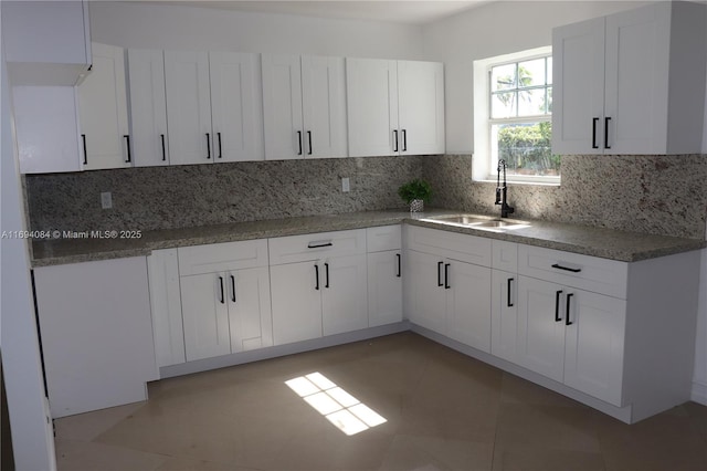 kitchen featuring decorative backsplash, sink, and white cabinets