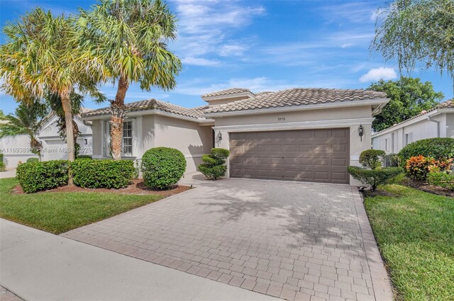 mediterranean / spanish-style house with a garage and a front lawn