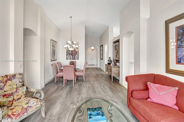 living room featuring lofted ceiling, a notable chandelier, and hardwood / wood-style floors