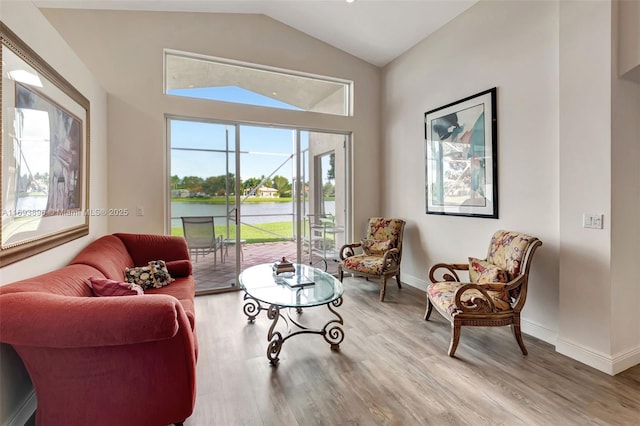 living area with a water view, light hardwood / wood-style flooring, and vaulted ceiling