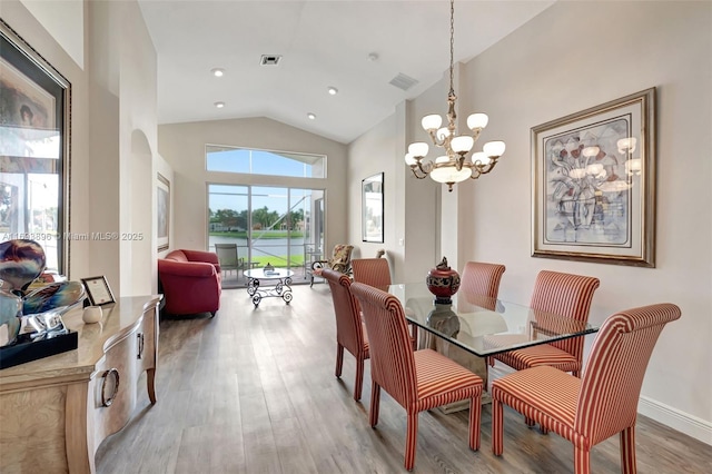 dining room featuring an inviting chandelier, high vaulted ceiling, and light hardwood / wood-style floors