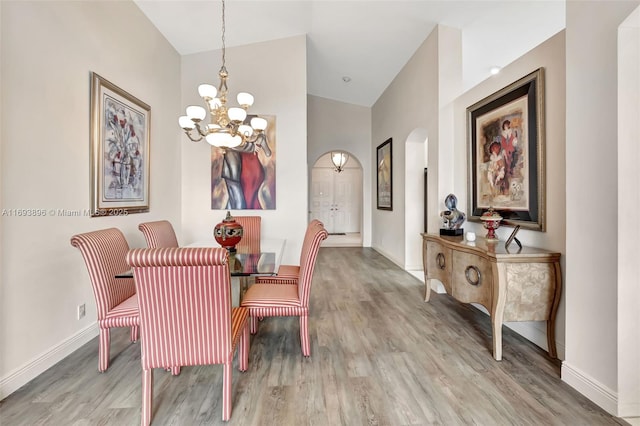 dining area featuring high vaulted ceiling, light hardwood / wood-style flooring, and an inviting chandelier