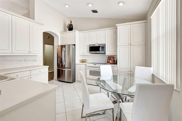 kitchen featuring white cabinets, light tile patterned floors, lofted ceiling, and stainless steel appliances