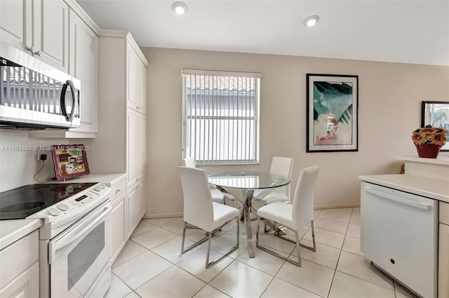 kitchen with light tile patterned floors, white cabinets, and white appliances