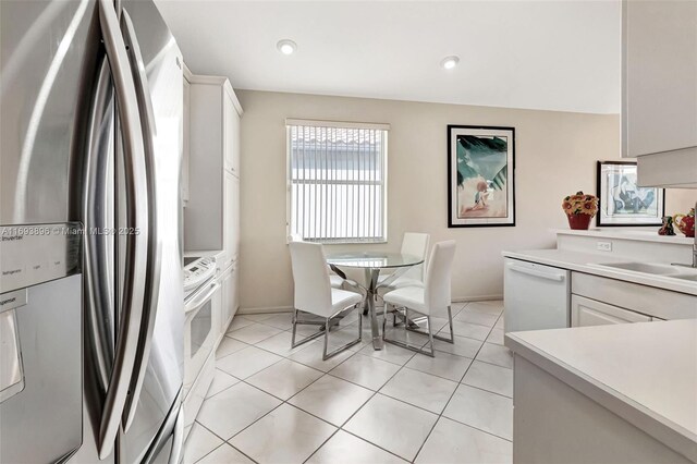 kitchen with sink, white appliances, white cabinets, and light tile patterned floors