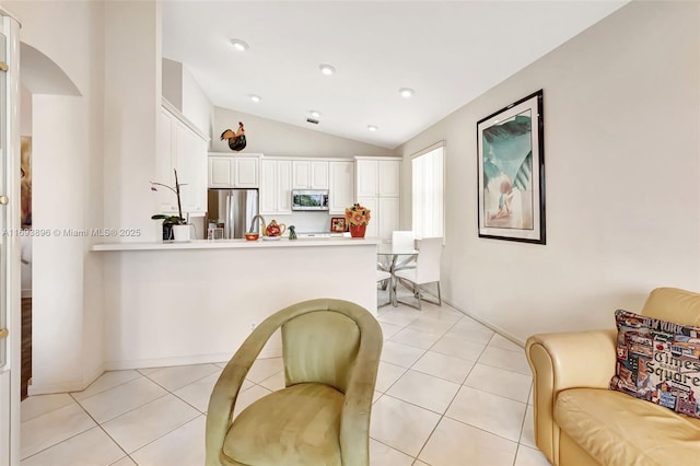 kitchen with light tile patterned floors, white cabinets, stainless steel appliances, and vaulted ceiling