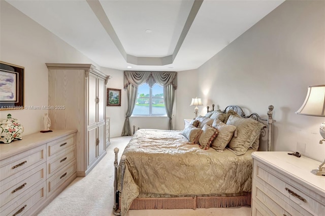 bedroom with light carpet and a raised ceiling