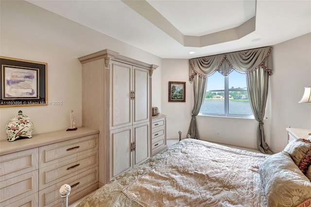 bedroom with a water view and a raised ceiling