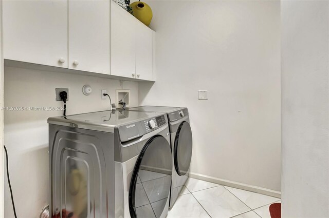 laundry area featuring washer and clothes dryer, cabinets, and light tile patterned flooring