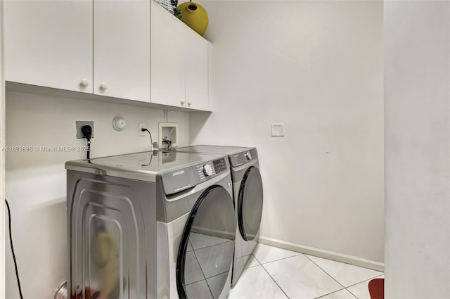 washroom with cabinets, washer and dryer, and light tile patterned floors