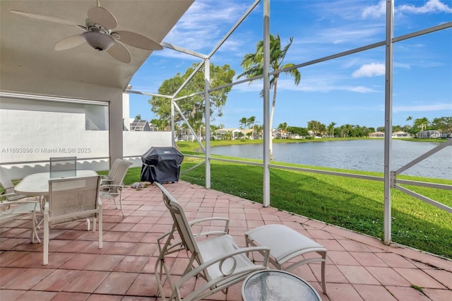 view of patio / terrace featuring glass enclosure, ceiling fan, a water view, and area for grilling