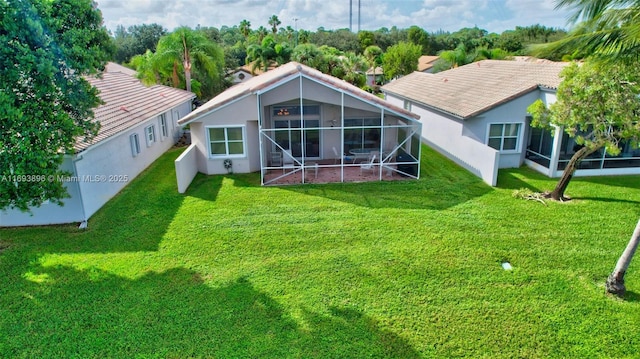 rear view of property with glass enclosure and a lawn