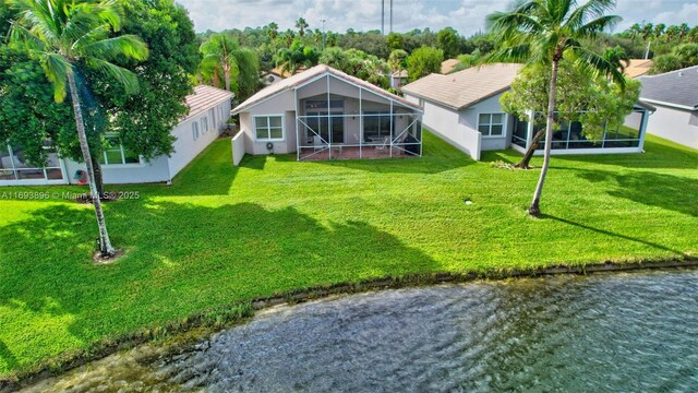 rear view of property with a lawn, a lanai, and a water view