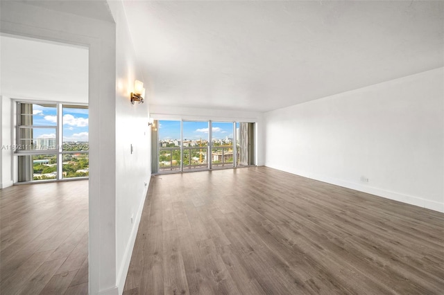 unfurnished living room with dark hardwood / wood-style flooring, a wall of windows, and a healthy amount of sunlight