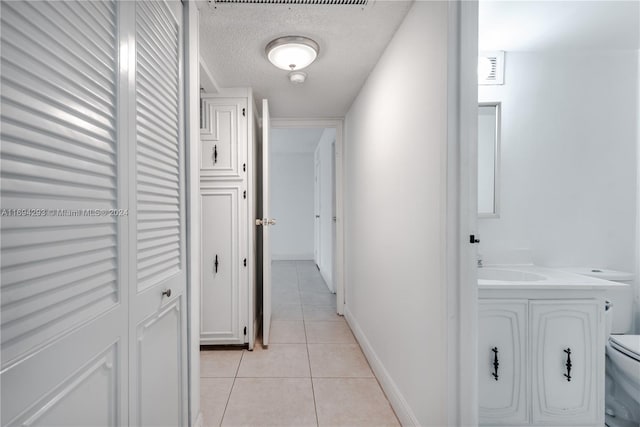 2000 Atlantic Shores Blvd Unit 107, Hallandale Beach, FL 33009 - corridor featuring light tile patterned floors, a textured ceiling, and baseboards