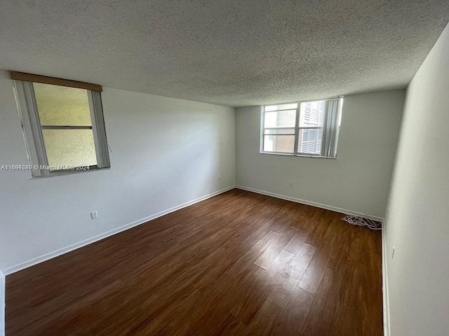 unfurnished room featuring a textured ceiling and dark hardwood / wood-style floors