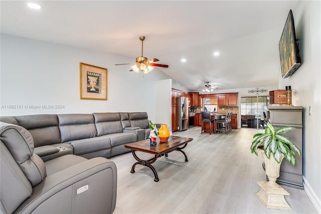 living room featuring ceiling fan, lofted ceiling, and light hardwood / wood-style flooring