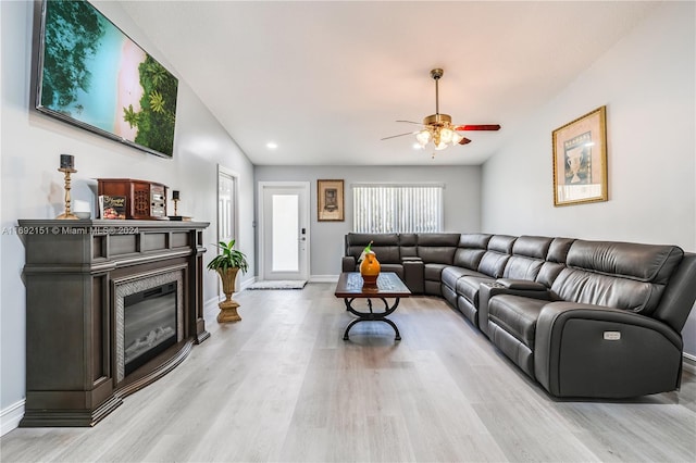 living room featuring ceiling fan, lofted ceiling, and light wood-type flooring