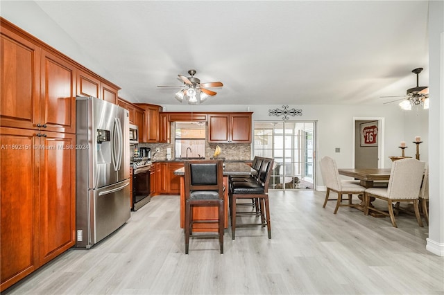 kitchen with sink, stainless steel appliances, light hardwood / wood-style flooring, decorative backsplash, and a breakfast bar