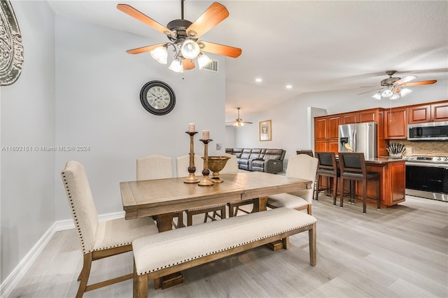 dining space featuring ceiling fan, light hardwood / wood-style flooring, and vaulted ceiling