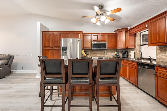 kitchen featuring decorative backsplash, light wood-type flooring, stainless steel appliances, and vaulted ceiling