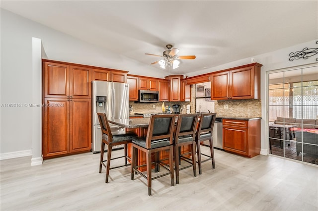 kitchen with ceiling fan, a center island, light hardwood / wood-style flooring, a breakfast bar area, and appliances with stainless steel finishes