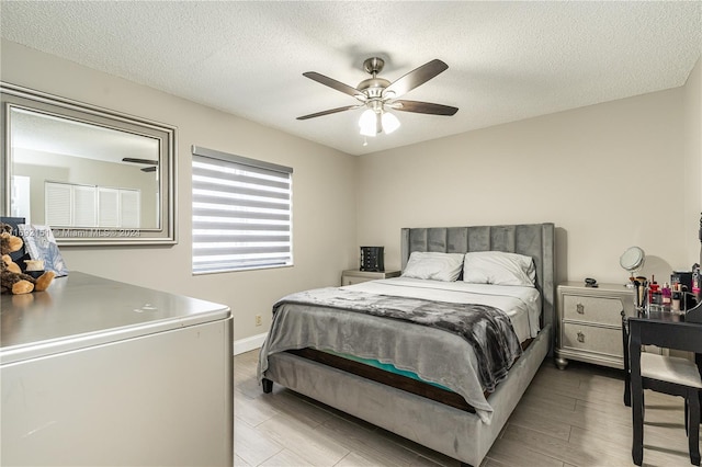 bedroom featuring ceiling fan, a textured ceiling, and light hardwood / wood-style flooring