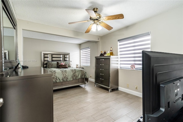 bedroom featuring ceiling fan, a textured ceiling, and light hardwood / wood-style flooring