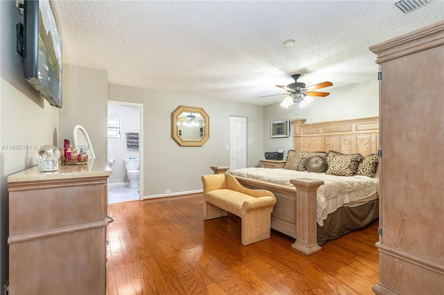 bedroom with hardwood / wood-style flooring, ceiling fan, a textured ceiling, and ensuite bath