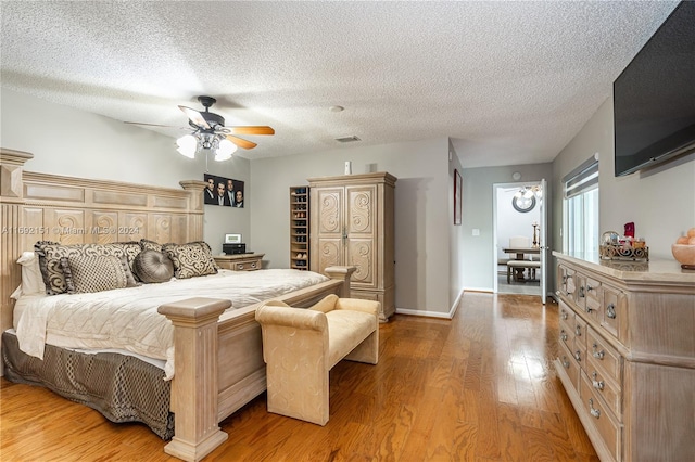 bedroom featuring ceiling fan, wood-type flooring, and a textured ceiling