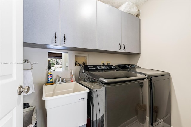 clothes washing area with cabinets, washing machine and dryer, and sink