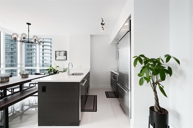 kitchen with pendant lighting, sink, kitchen peninsula, a notable chandelier, and stainless steel built in refrigerator