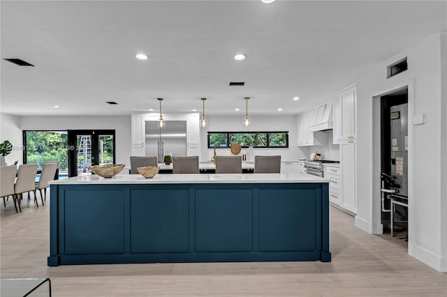 kitchen featuring white cabinets, decorative light fixtures, stainless steel appliances, and a wealth of natural light